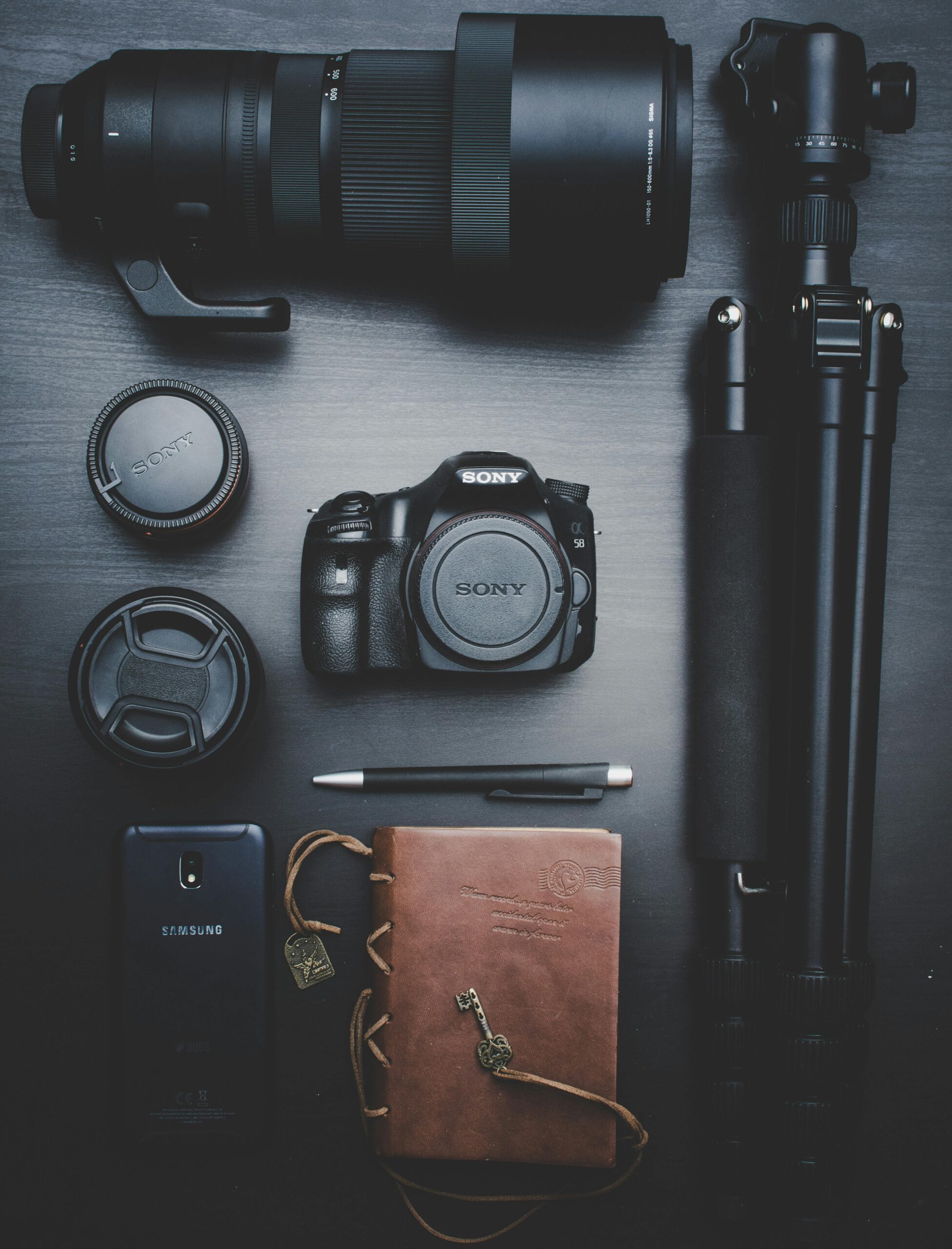 Flat lay of photography equipment including a DSLR, lenses, and accessories on a table.