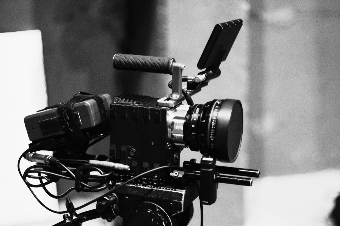 Black and white image of a Cinematography resting on a tripod head camera